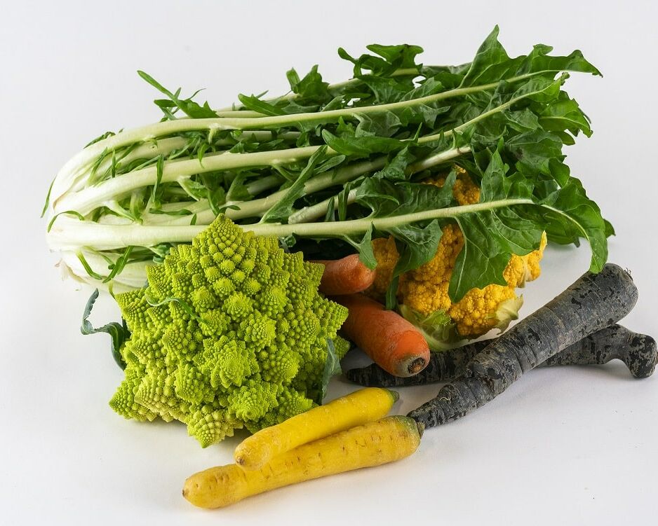 Fumagalli Danilo Ingrosso Ortofrutta Un assortimento di verdure, tra cui verdure a foglia verde, broccoli romanesco, carote gialle e arancioni, carote viola e cavolfiori gialli provenienti da Fumagalli Danilo Besana in Brianza — il vostro grossista di ortofrutta di fiducia — disposte su uno sfondo bianco. Ristorazione Professionale - GDO - retail - privati