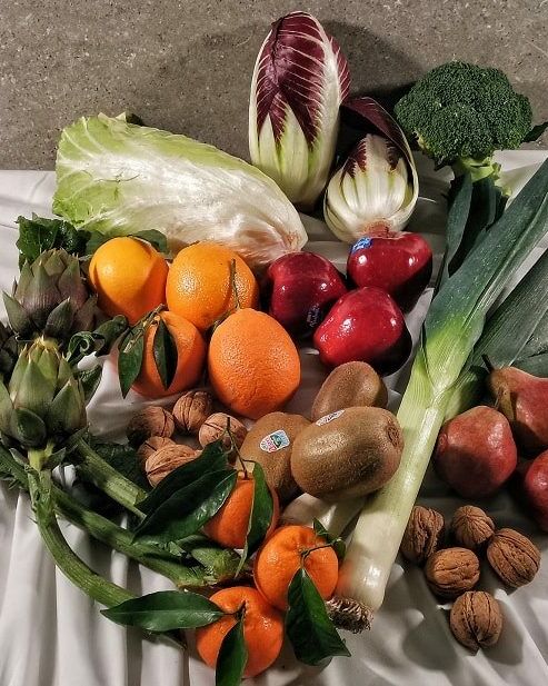 Fumagalli Danilo Ingrosso Ortofrutta Frutta fresca, verdura e frutta secca assortite — tra cui arance, mele, porri, broccoli, carciofi, indivia, pere, kiwi, mandarini, noci e lattuga — disposte su una tovaglia bianca fornita da Fumagalli Danilo Besana, grossista ortofrutta della Brianza. Ristorazione Professionale - GDO - retail - privati