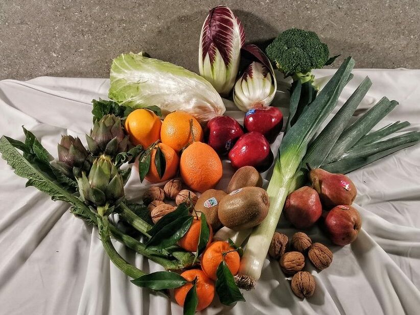 Fumagalli Danilo Ingrosso Ortofrutta Frutta fresca, verdura e frutta secca assortite &mdash; tra cui arance, mele, porri, broccoli, carciofi, indivia, pere, kiwi, mandarini, noci e lattuga &mdash; disposte su una tovaglia bianca fornita da Fumagalli Danilo Besana, grossista ortofrutta della Brianza. Ristorazione Professionale - GDO - retail - privati