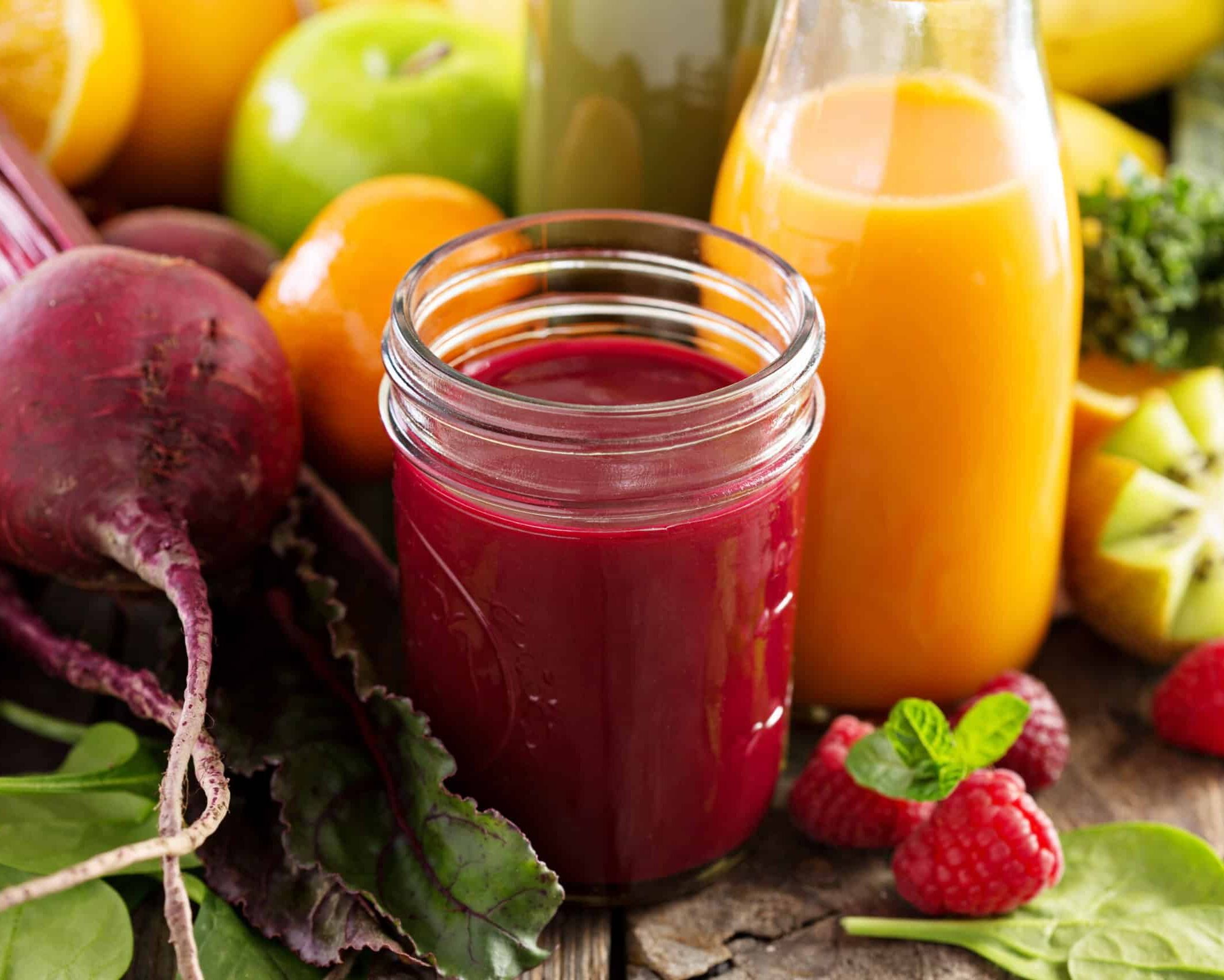 Fumagalli Danilo Ingrosso Ortofrutta Un barattolo di succo rosso e una bottiglia di succo d’arancia sono appoggiati su un tavolo di legno circondato da frutta e verdura fresca come barbabietole, mele, arance, kiwi, lamponi e verdure a foglia verde: un'immagine che incarna alla perfezione la vivace selezione offerta da Fumagalli Danilo Besana in Brianza, il vostro grossista di fiducia per la ristorazione a base di ortofrutta. Ristorazione Professionale - GDO - retail - privati