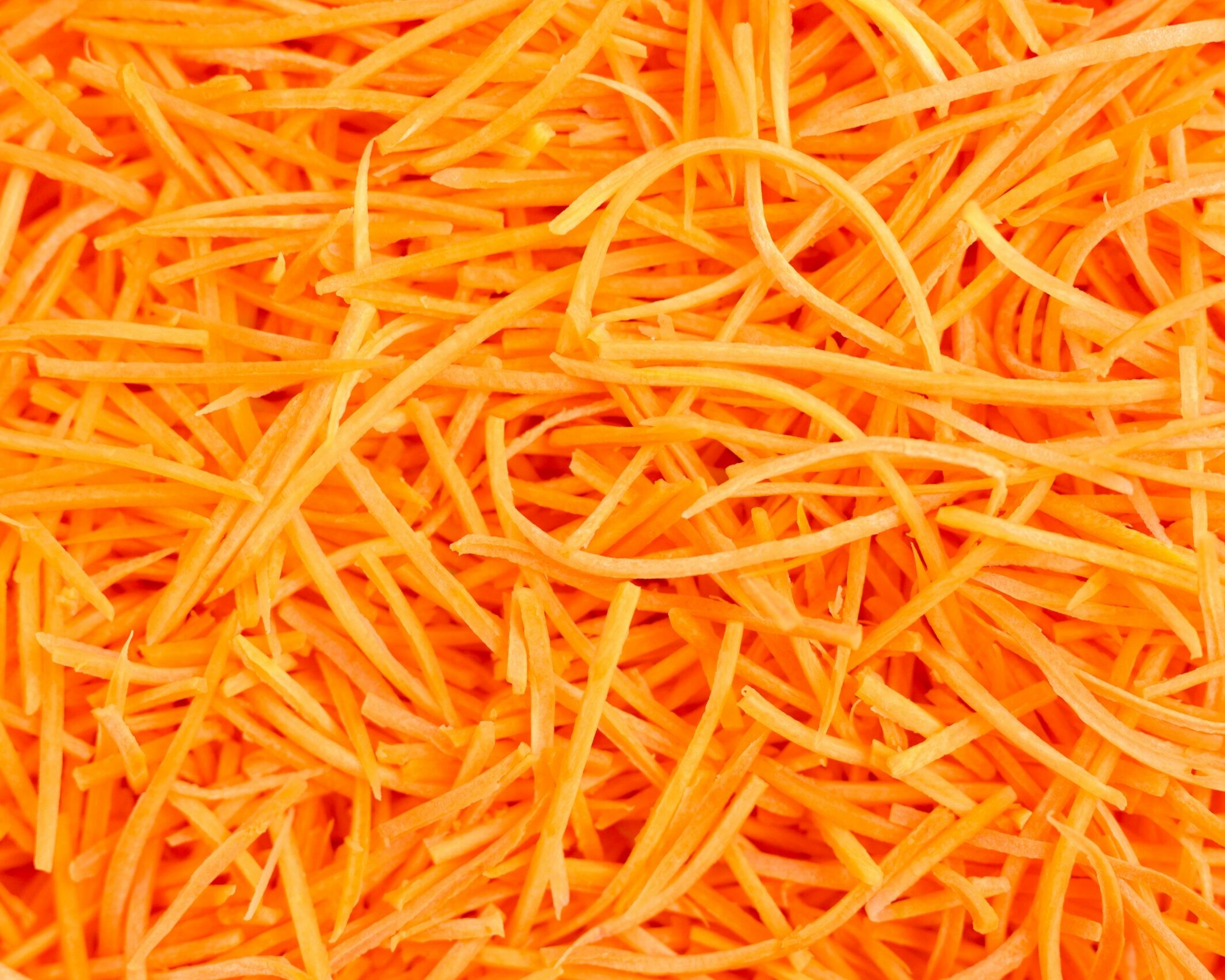 Fumagalli Danilo Ingrosso Ortofrutta Un primo piano di una montagna di carote arancioni tagliate a julienne sottili, che riempie l’intera inquadratura, mette in risalto la freschezza spesso garantita dai grossisti ortofrutticoli come Fumagalli Danilo Besana in Brianza. Ristorazione Professionale - GDO - retail - privati